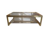 a glass and brass coffee table on a white background
