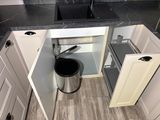 a trash can in the corner of a kitchen cabinet