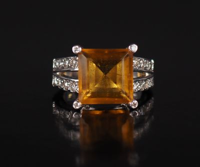 an orange sapphire and diamond ring on a black surface