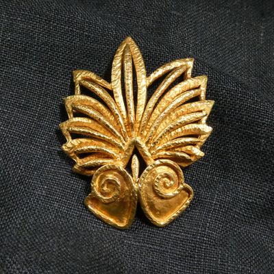 a close up of a gold leaf brooch on a black cloth