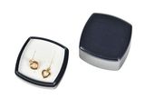 pair of black and gold earrings in a square box on a white surface