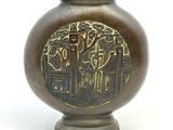 un vase en bronze orné d'un motif sur fond blanc