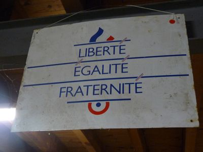 une pancarte sur laquelle on peut lire « liberté, égalité, fraternité » et « fratermite », suspendue au plafond