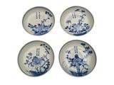 four blue and white plates with flowers on them on a white surface