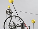 a sculpture of a spinning bicycle with yellow balls on top of it