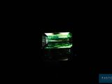 a close up of a green emerald stone on a black surface
