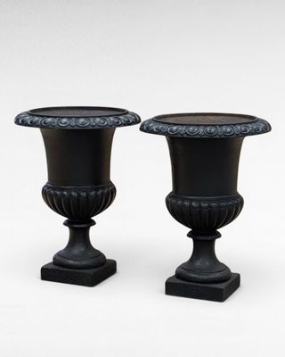 pair of black urns on pedestals on a white background