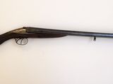 un vieux fusil posé sur une surface blanche, muni d'une crosse en bois