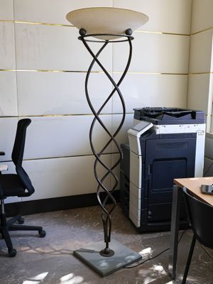 a lamp that is sitting on a stand in the corner of a room
