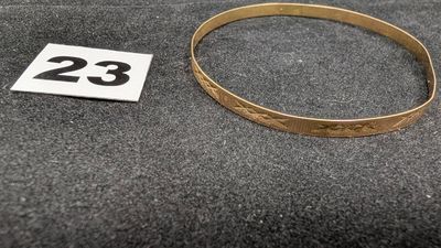 un gros plan d'un bracelet en or sur lequel figure le chiffre 23