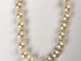 a close up of a pearl necklace on a white surface