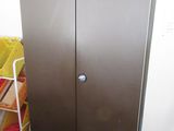 a metal door in the corner of a room next to a shelf