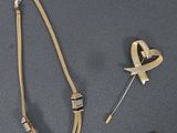 un collier, un bracelet et une broche posés sur un fond gris