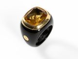 a close up of a black and gold ring on a white surface