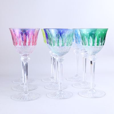 plusieurs verres à vin de couleurs différentes sont alignés sur une surface blanche