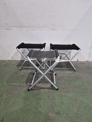 trois chaises pliantes placées dans une pièce, avec un mur derrière elles