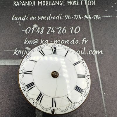 une horloge dont le cadran porte des chiffres romains, posée par terre