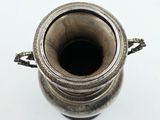 a silver vase that is sitting on a white surface