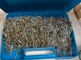 a blue box filled with lots of nails on top of a table