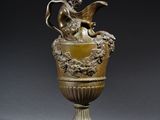 un vase antique en bronze surmonté d'une figure ailée