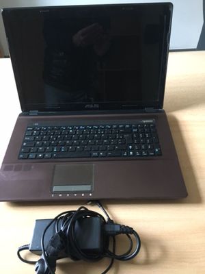 an open laptop computer sitting on top of a wooden desk next to a charger