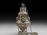 un vieux vase en argent entouré d'une chaîne, posé sur une table