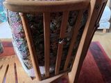 a wooden chair with a floral seat pad on a rug