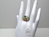 une main blanche ornée d'une bague sertie de pierres multicolores