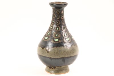a brown vase with green dots on it on a white background