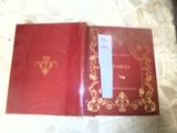 a red book with gold writing on it sitting on a bed
