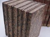 several old books are stacked on top of each other on a white surface