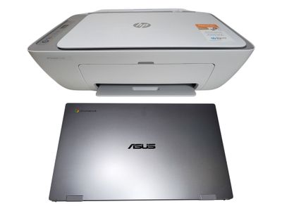 L'ordinateur portable est posé à côté de l'imprimante, sur la surface blanche.