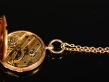 an image of a close up of a gold pocket watch on a chain