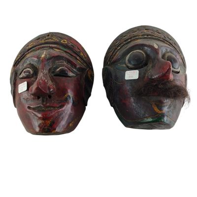 une paire de masques en bois dont les visages sont peints sur fond blanc
