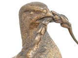 bronze statue of a bird with a mouse in its beak