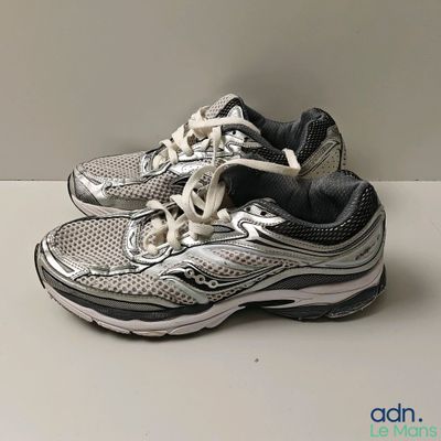 une paire de chaussures de course Saucony posées sur une surface blanche