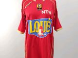 Le t-shirt est rouge et jaune, avec un logo dessus.