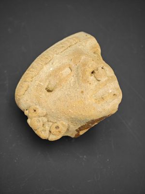 une ancienne tête d'homme sculptée dans la pierre, sur un fond noir