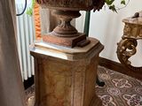 a plant in a vase on a pedestal in a room