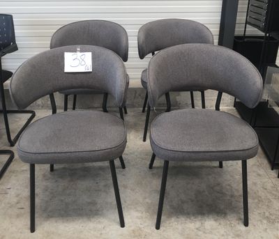 quatre chaises grises aux pieds noirs, avec une pancarte fixée à l'arrière