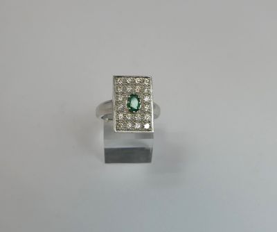 a close up of a ring with a green stone surrounded by white diamonds
