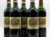 six bottles of wine are lined up in a row on a white surface