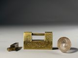 a gold lock and a pair of keys on a white surface