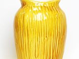 a yellow vase that is sitting on a white surface