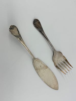 two silver spoons and a fork on a white surface