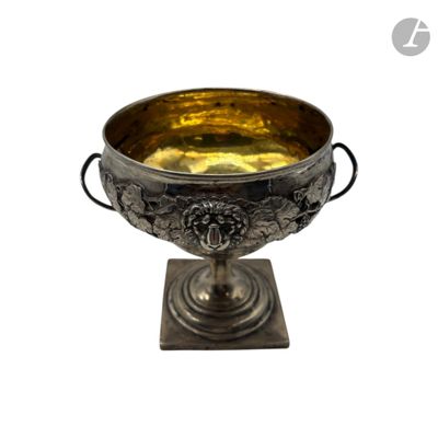 une coupe en argent posée sur un socle en métal, sur fond blanc