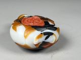 an orange, white, and black bead with a bird on top of it
