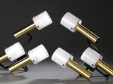 trois lampes blanches et dorées posées sur une table, sur fond noir