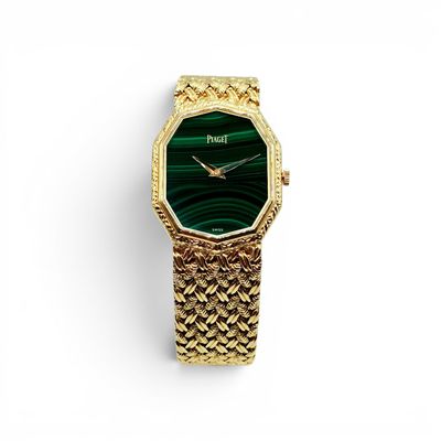 a close up of a gold watch with a green face
