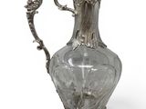 an antique silver plated glass pitcher on a stand with a handle